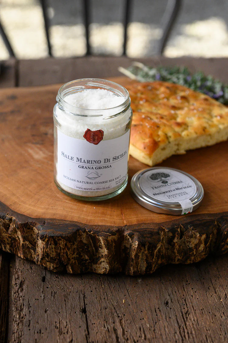 Jar of cream with a label on a wooden surface with bread in the background