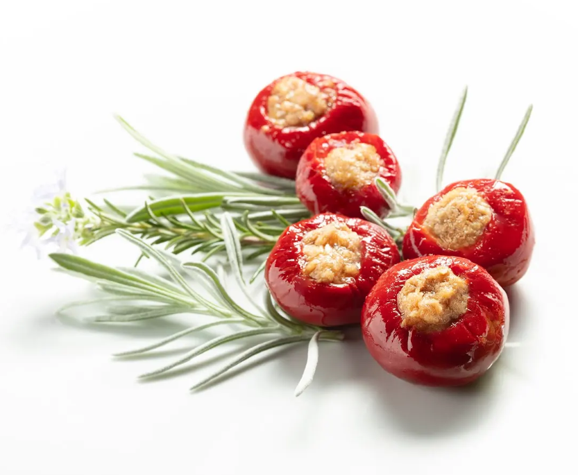Red stuffed tomatoes with a herb garnish on a white background